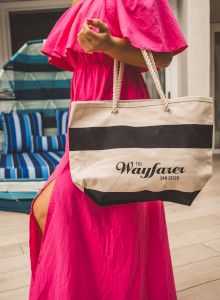 A small crossbody bag with a "Wagons" (Wagons?) logo sits on a pink chair, against a backdrop of blue-striped chairs.
