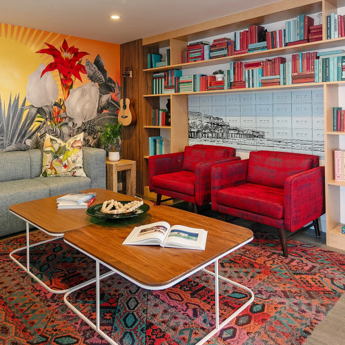 A cozy, colorful living room with vintage furniture, patterned rug, a small wooden coffee table, plants, and warm lighting, cheery and inviting.