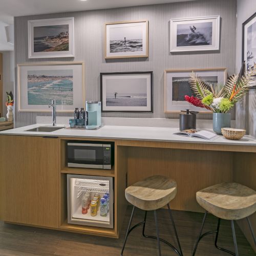 A cozy, wood-furnished reception area with framed pictures on the wall, a desk, and two stools under a counter.